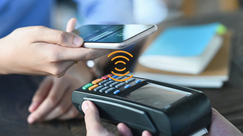 smart phone held near payment device with icon showing NFC connection between the two