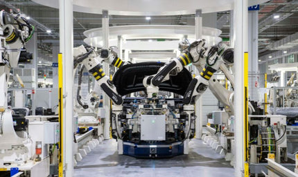 Industrial robots assembling a vehicle on an automated production line inside a modern factory, illustrating smart manufacturing and connected industrial systems.