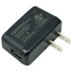 A black power supply adapter with two metal pins, featuring white printed specifications and certification logos on its top surface and USB-A connector on the side.